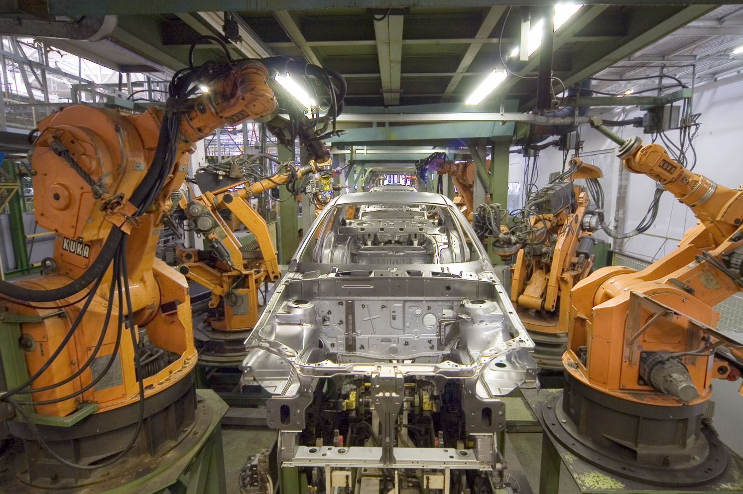 Célula robótica industrial con múltiples brazos manipuladores en entorno de fabricación